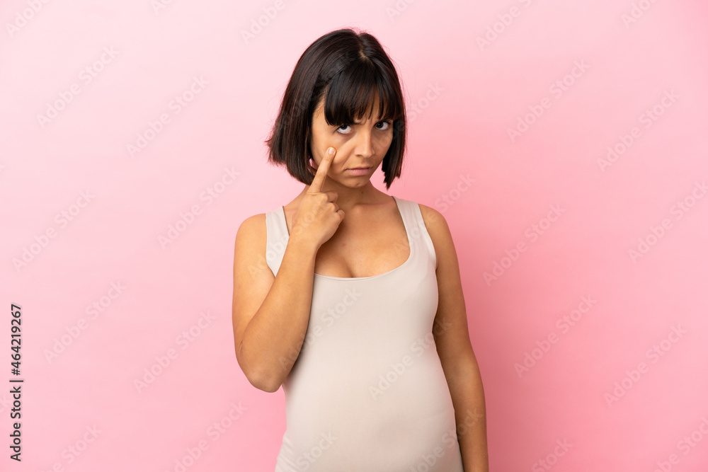 Young pregnant woman over isolated pink background showing something Young pregnant woman over isolated pink background showing something