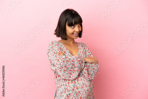 Young pregnant woman over isolated pink background looking to the side © luismolinero