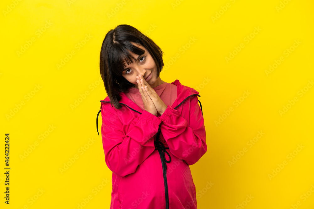 Young pregnant woman over isolated yellow background keeps palm together. Person asks for something Young pregnant woman over isolated yellow background keeps palm together. Person asks for something