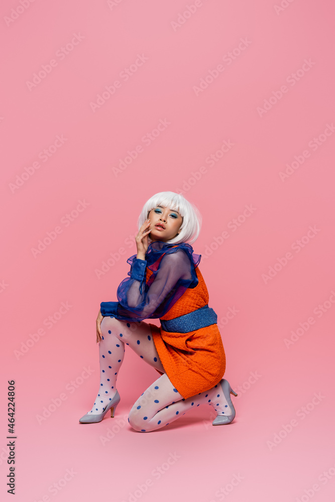 Stylish asian pop art woman looking at camera on pink background