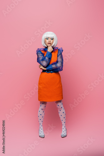 Pretty asian pop art woman in white wig looking at camera on pink background