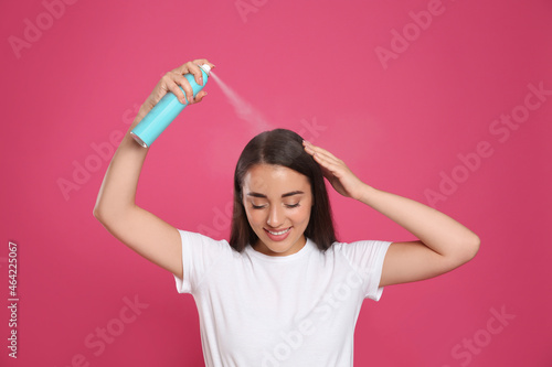 Cuadro en lienzo Young woman applying dry shampoo against pink background