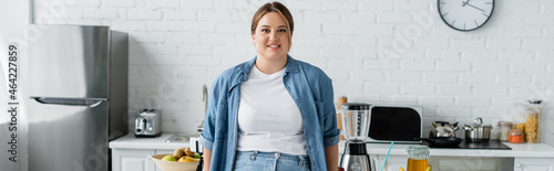 Positive woman with overweight standing near food in kitchen, banner