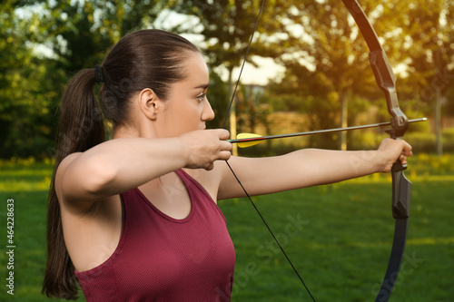Obraz na plátně Woman with bow and arrow practicing archery in park
