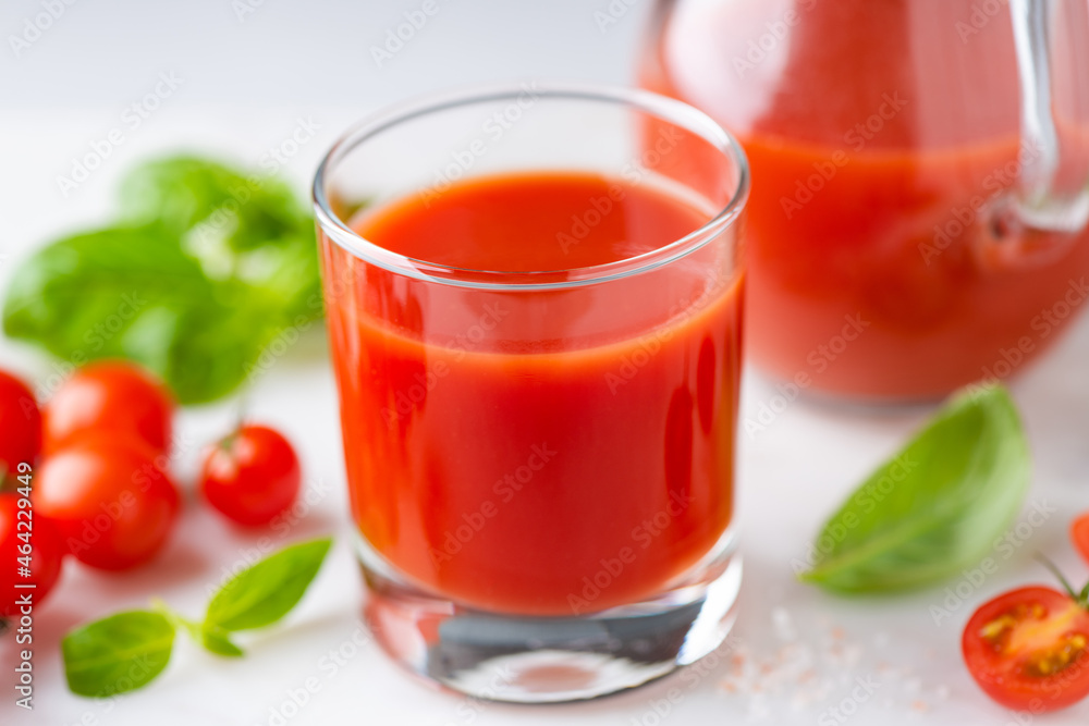 Salted tomato juice in glass on white stone background, closeup view Salted tomato juice in glass on white stone background, closeup view