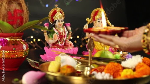 Hands Of Girl In Bangles Holding Clay Diya Deep Dia Lamp Illuminated With Pooja Thali, Flowers, Mithai, Agarbatti And Doing Aarti. Diwali Puja , New Year, Deepawali Or Shubh Deepavali Theme photo