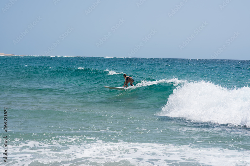 Woman seen riding wave with her surfboard