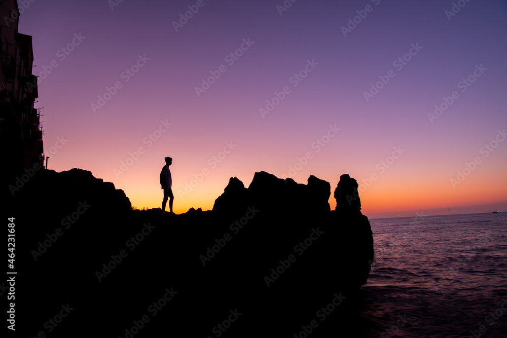 young man walking on rocky terrain at colorful sunset