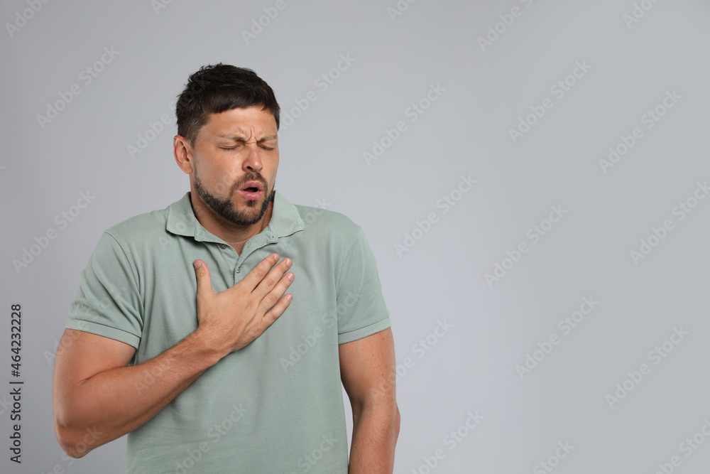 Man suffering from pain during breathing on grey background, space for text Man suffering from pain during breathing on grey background, space for text