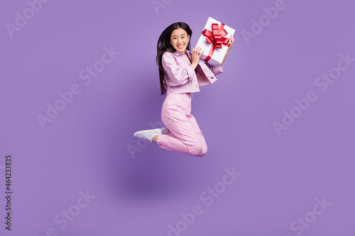 Full body profile photo of cool millennial brunette lady jump hold present wear jacket jeans sneakers isolated on violet background