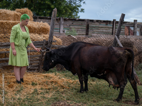 Woman with green hair caring for cows and milking milk from them