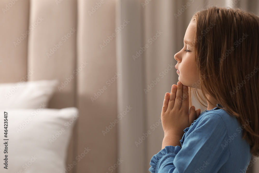 Cute little girl saying bedtime prayer at home. Space for text Cute little girl saying bedtime prayer at home. Space for text