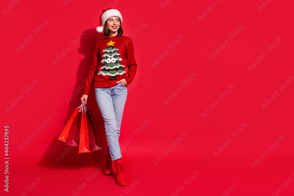 Photo of dreamy pretty lady dressed print pullover smiling walking holding noel bargains looking empty space isolated red color background Photo of dreamy pretty lady dressed print pullover smiling walking holding noel bargains looking empty space isolated red color background
