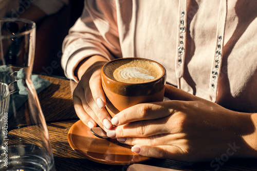 cappuccino cup in women's hands in a cafe