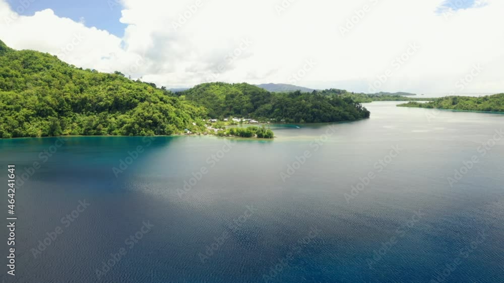 Aerial view of flying across a harbour to a tropical coastal village. Aerial view of flying across a harbour to a tropical coastal village.