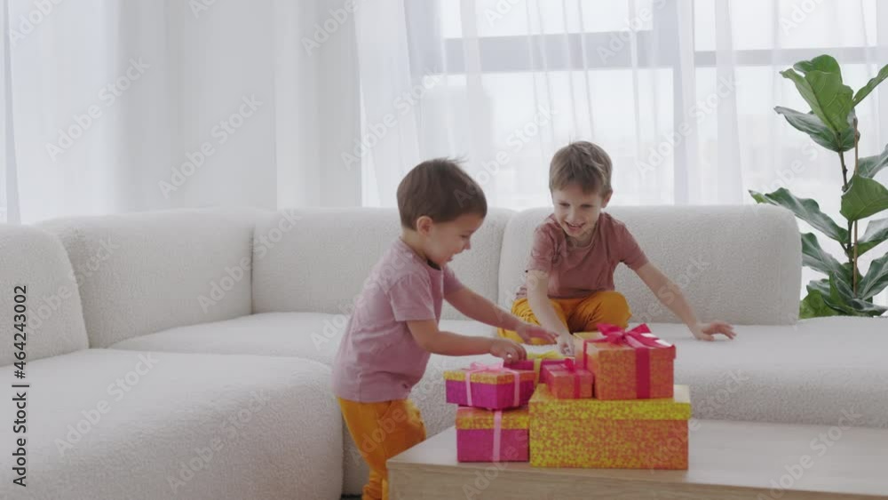 The Season of Giving concept. Two kids are opening Christmas gift boxes, playing at home Winter time, New Year presents and seasonal tradition - gift-giving. The Season of Giving concept. Two kids are opening Christmas gift boxes, playing at home Winter time, New Year presents and seasonal tradition - gift-giving.