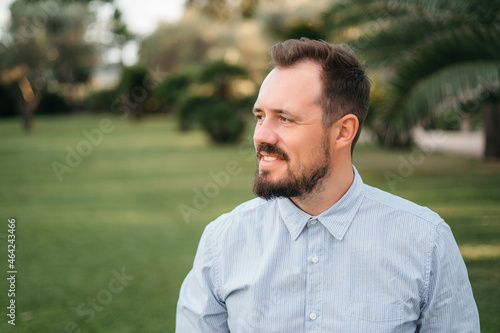 Portrait of happy mature man looking at camera outdoor. Senior businessman with beard feeling confident at sunset. Closeup face of business man smiling with city in background.
