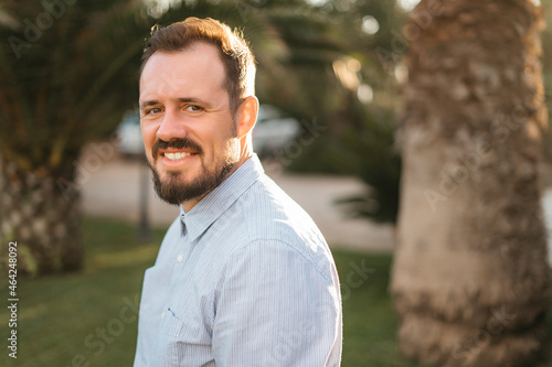 Portrait of happy mature man looking at camera outdoor. Senior businessman with beard feeling confident at sunset. Closeup face of business man smiling with city in background. © Oleksandr