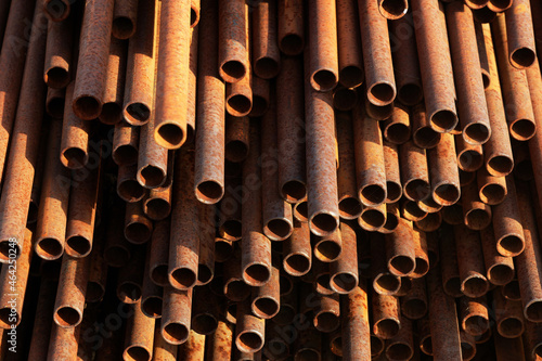 Many small-diameter metal pipes for gasification and construction lie in a stack in an open warehouse on the street. Solid industrial background for the supplier of metal pipes. New products.