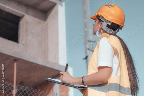 Arquitecta de obra estudiando el perimetro del edificio para su construcción junto con otros empleados de obra asegurados con sus cascos de protección mientras se planifica la maquetación