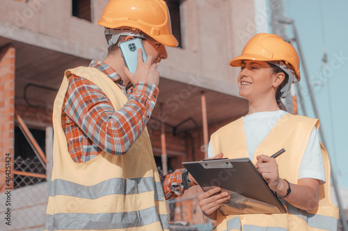 Empleados de construcción de ingeniería y arquitectura realizando una llamada de su teléfono móvil para contactar con la inmobiliaria y consultar los planos e ideas 