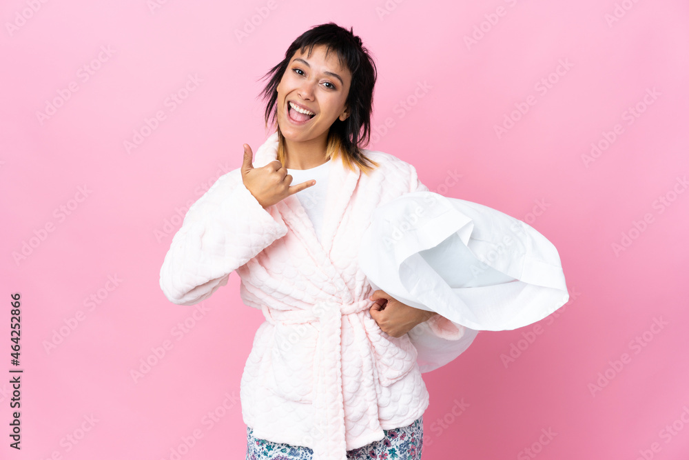 Young Uruguayan woman in pajamas over isolated pink background making phone gesture Young Uruguayan woman in pajamas over isolated pink background making phone gesture