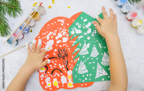Child making a greeting card Craft for children. Nice greeting card with a Christmas snowy forest. . Top view