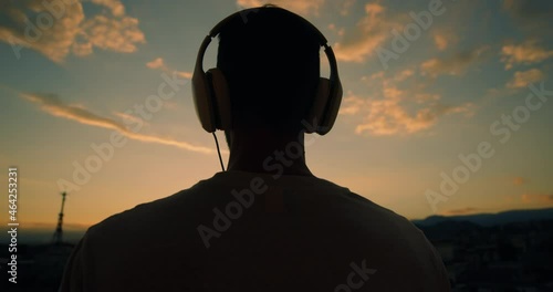 Sagoma di un ragazzo al tramonto con cuffie photo