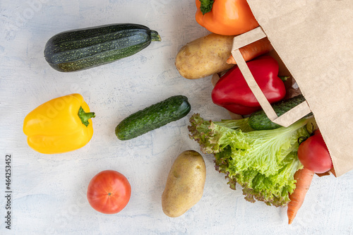 Eco concept for shopping, food preparation. paper bag with carrots, cucumbers, bell peppers, patatoes, lettuce and tomatoes. flat lay on white textared table. photo