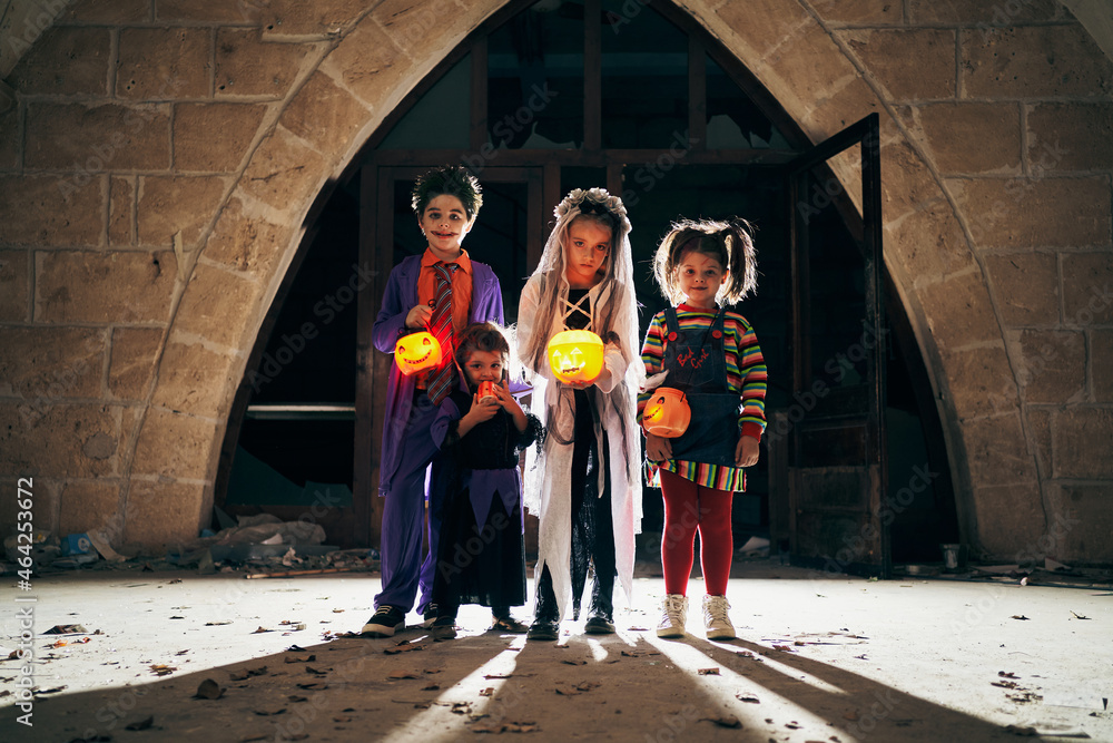 Kids in Halloween costumes with glowing buckets in darkness