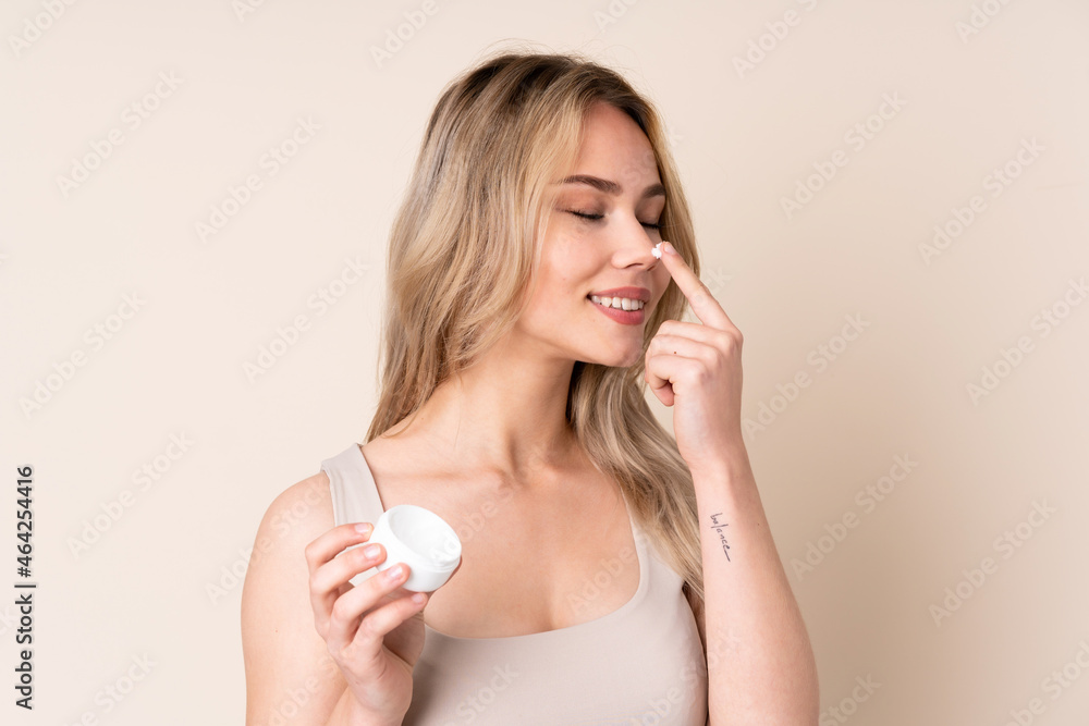 Teenager blonde girl with moisturizer over isolated background Teenager blonde girl with moisturizer over isolated background