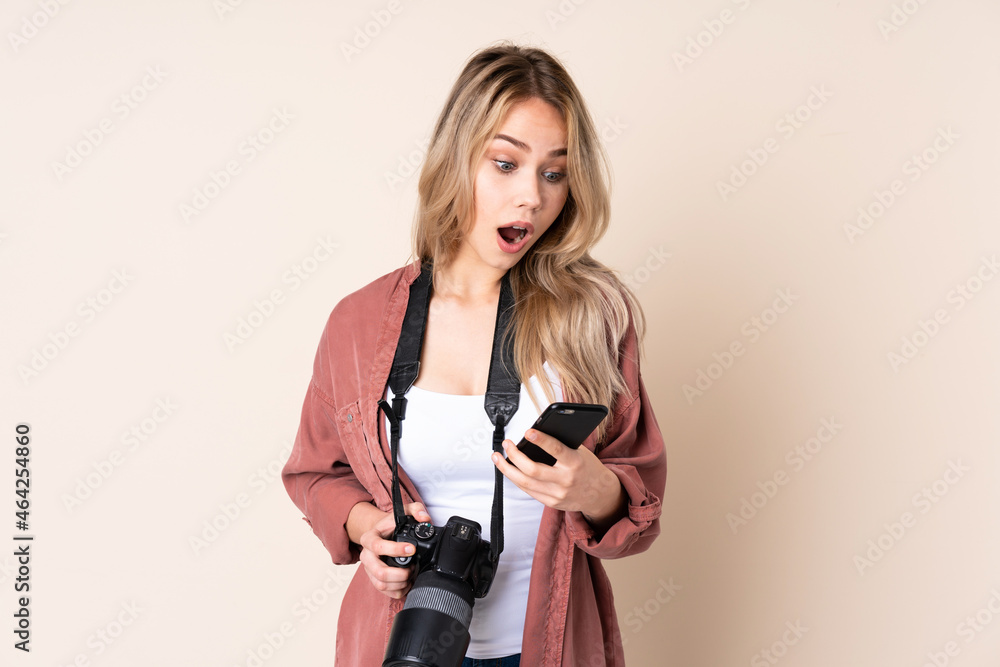 Young photographer girl over isolated background surprised and sending a message Young photographer girl over isolated background surprised and sending a message