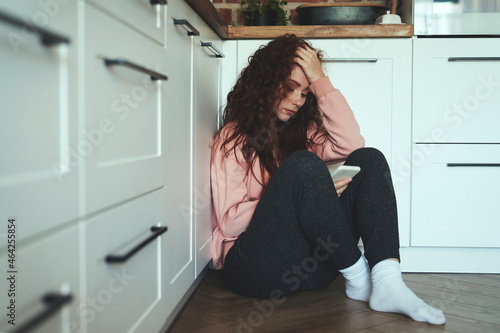 Obraz na plátně Young caucasian woman using mobile phone on kitchen floor