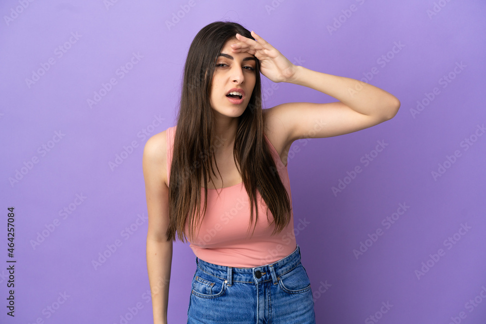 Young caucasian woman isolated on purple background looking far away with hand to look something