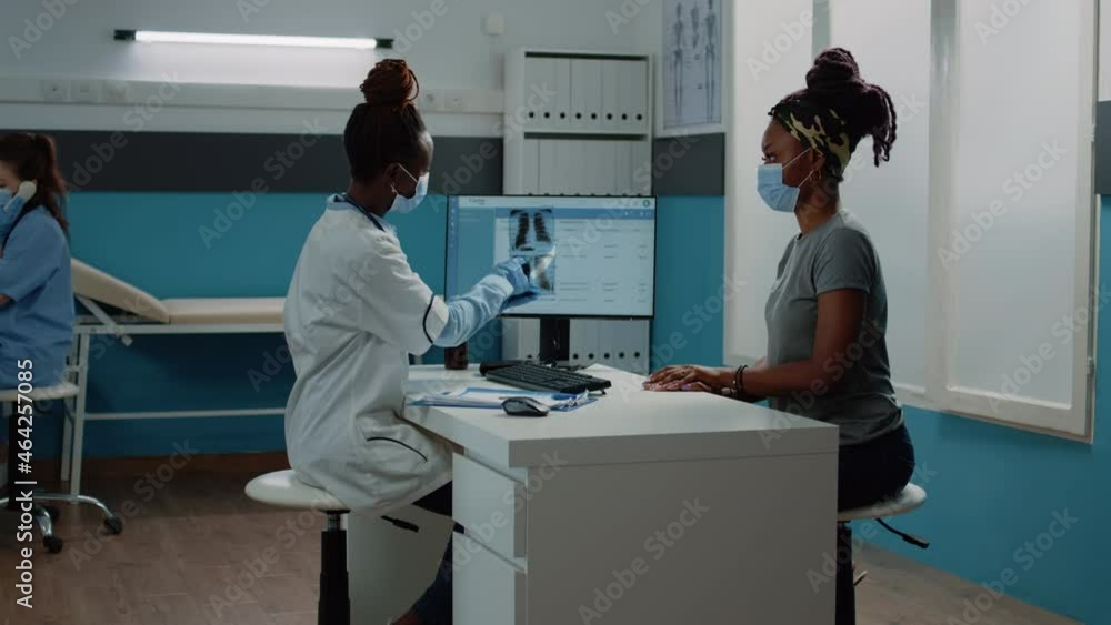 Medic holding radiography for examination with patient during coronavirus pandemic. Doctor explaining x ray scan results and diagnosis to woman, wearing face masks for protection. Medic holding radiography for examination with patient during coronavirus pandemic. Doctor explaining x ray scan results and diagnosis to woman, wearing face masks for protection.