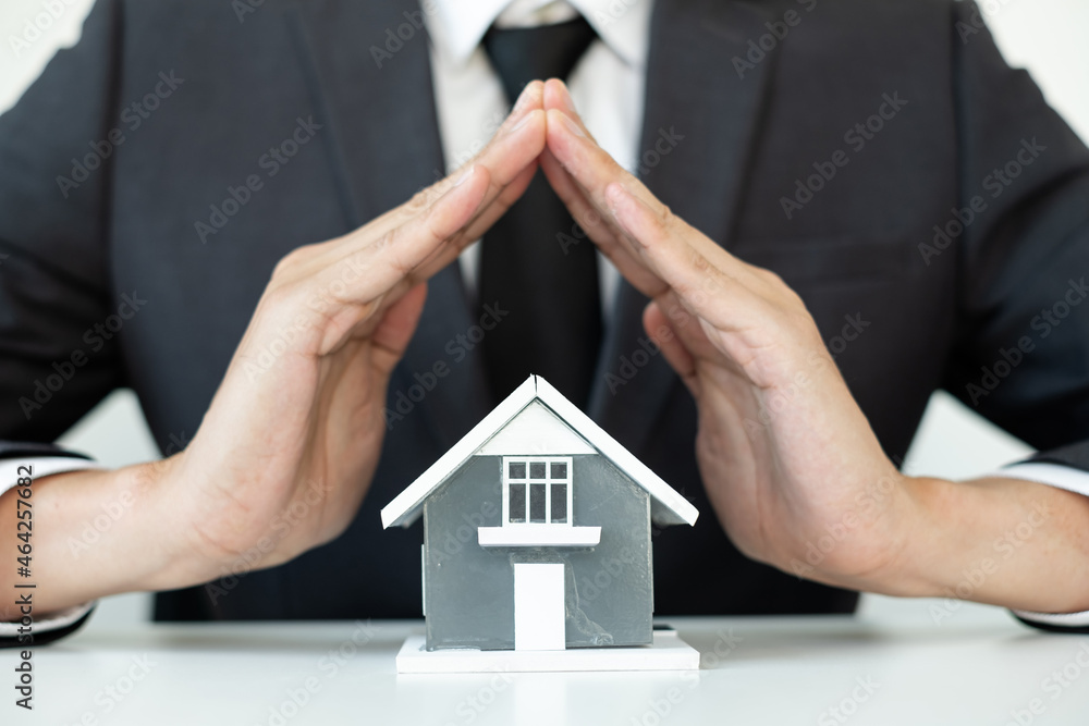 The house is covered by the hands of a real estate agent to protect the house for customers, homebuyers, insurance, ready give to with new owner. Real estate Home insurance concept The house is covered by the hands of a real estate agent to protect the house for customers, homebuyers, insurance, ready give to with new owner. Real estate Home insurance concept