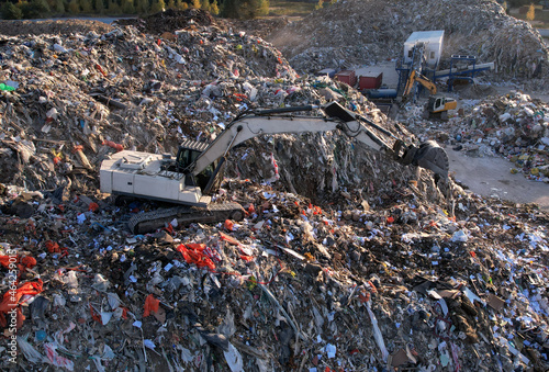 Landfill with Construction and Demolition waste (CDW). Trash disposal for recycling and re-use. Excavator working on industrial landfill. Recycling of building waste materials. Secondary raw.
