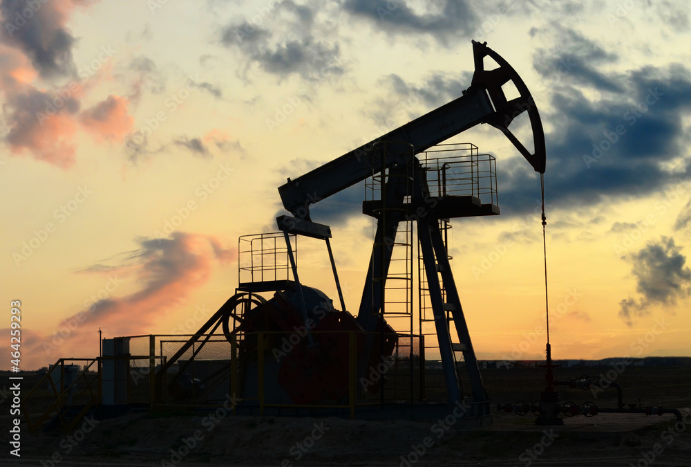 Crude oil pump jack at oilfield on sunset backround. Fossil crude output and fuels oil production. Oil drill rig and drilling derrick. Global crude oil Prices, energy, petroleum demand Crude oil pump jack at oilfield on sunset backround. Fossil crude output and fuels oil production. Oil drill rig and drilling derrick. Global crude oil Prices, energy, petroleum demand
