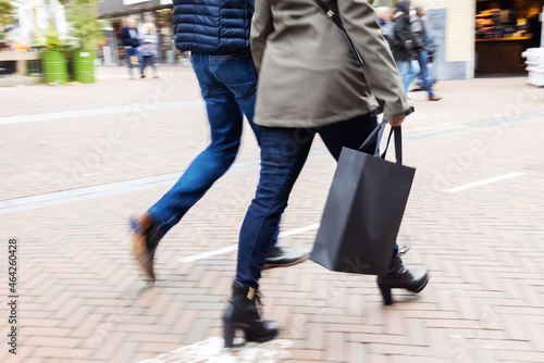 picture with camera made motion blur effect of legs of a couple walking on a shopping street