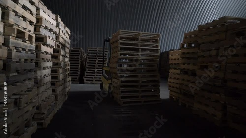 Worker is driving the elecric forklift. Loader and wooden pallet with boxes when loading.