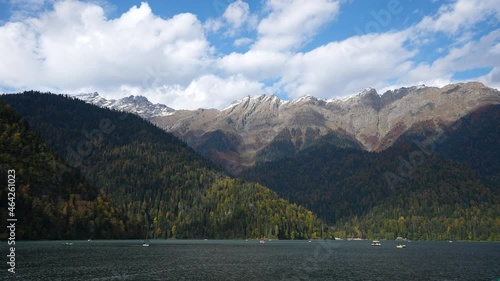 Timelapse of moving clouds in sky and sailing boats on lake surface. Mountain highland resort with wild wood forests background. Breathtaking view on amazing resort landscape, movement in time-lapse. photo