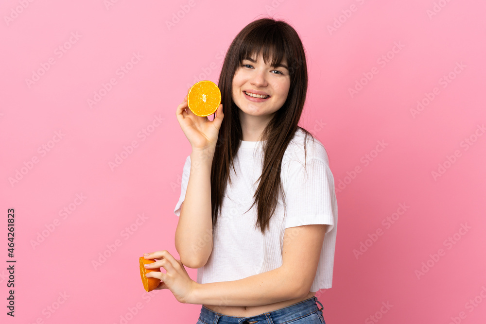 Young Ukrainian woman isolated on pink background holding an orange Young Ukrainian woman isolated on pink background holding an orange