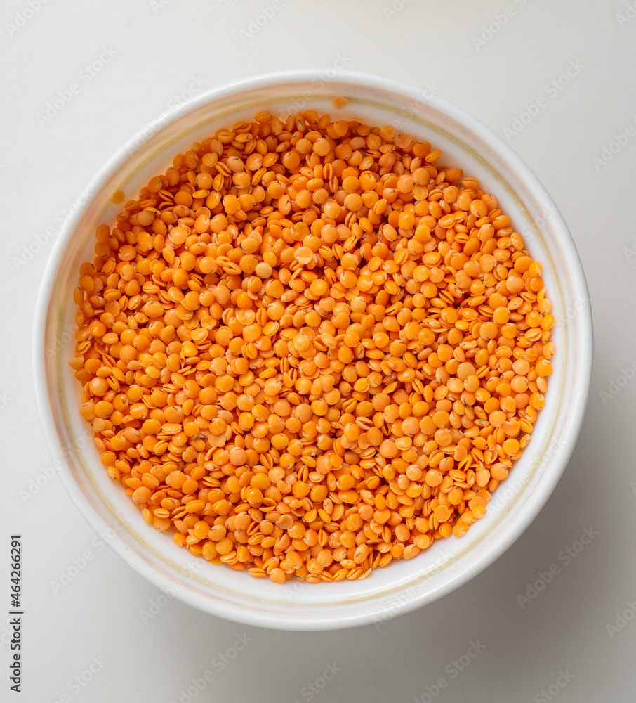 White Bowl filled with raw red lentil on white background White Bowl filled with raw red lentil on white background