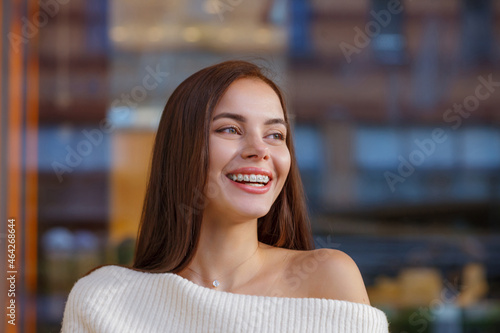 Emotional portrait of a beautiful happy smiling young woman with braces. girl with bracket system posing in city outdoor. Brace, bracket, dental care, malocclusion, orthodontic health concept, blurred