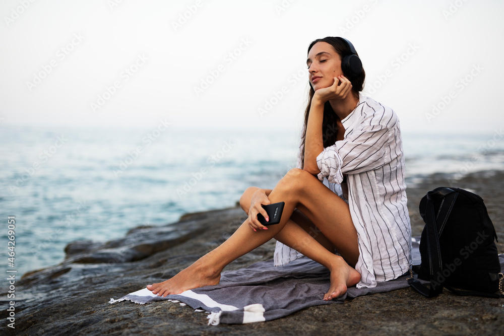 Hot woman relaxing on the sandy beach. Beautiful woman with headphones listening the music. Hot woman relaxing on the sandy beach. Beautiful woman with headphones listening the music.