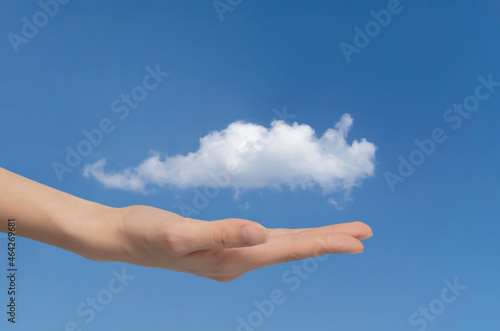 Woman's hand holds cloud in the palm of her hand, close-up on blue sky. Concept of data exchange and communication