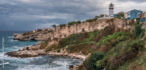 Photos View of lighthouse at seashore against cloudy sky