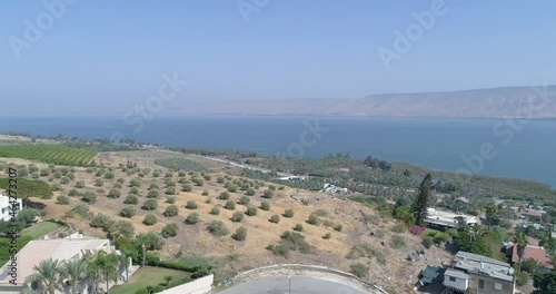 Aerial shot at sunset above Golan Heights and Tiberias with Galilee sea or Kinneret at Jordan valley in North of Israel. Drone above open fields with orange green landscapes and mountains with clear