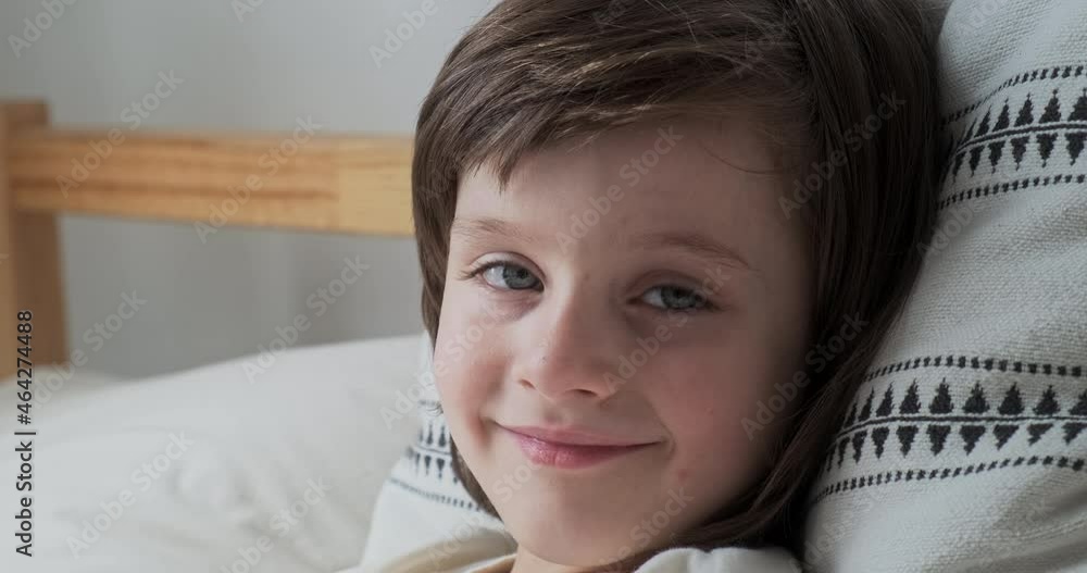 Portrait cute little boy with blue eyes and brunette hair lying on comfortable pillow relaxing at home. Close up face of cheerful European male preschooler kid resting on bed enjoying happy childhood Portrait cute little boy with blue eyes and brunette hair lying on comfortable pillow relaxing at home. Close up face of cheerful European male preschooler kid resting on bed enjoying happy childhood