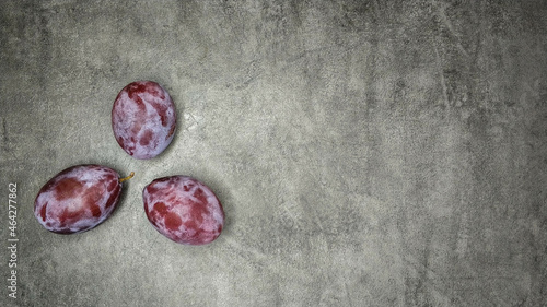 Three fresh plums on gray marble background. photo